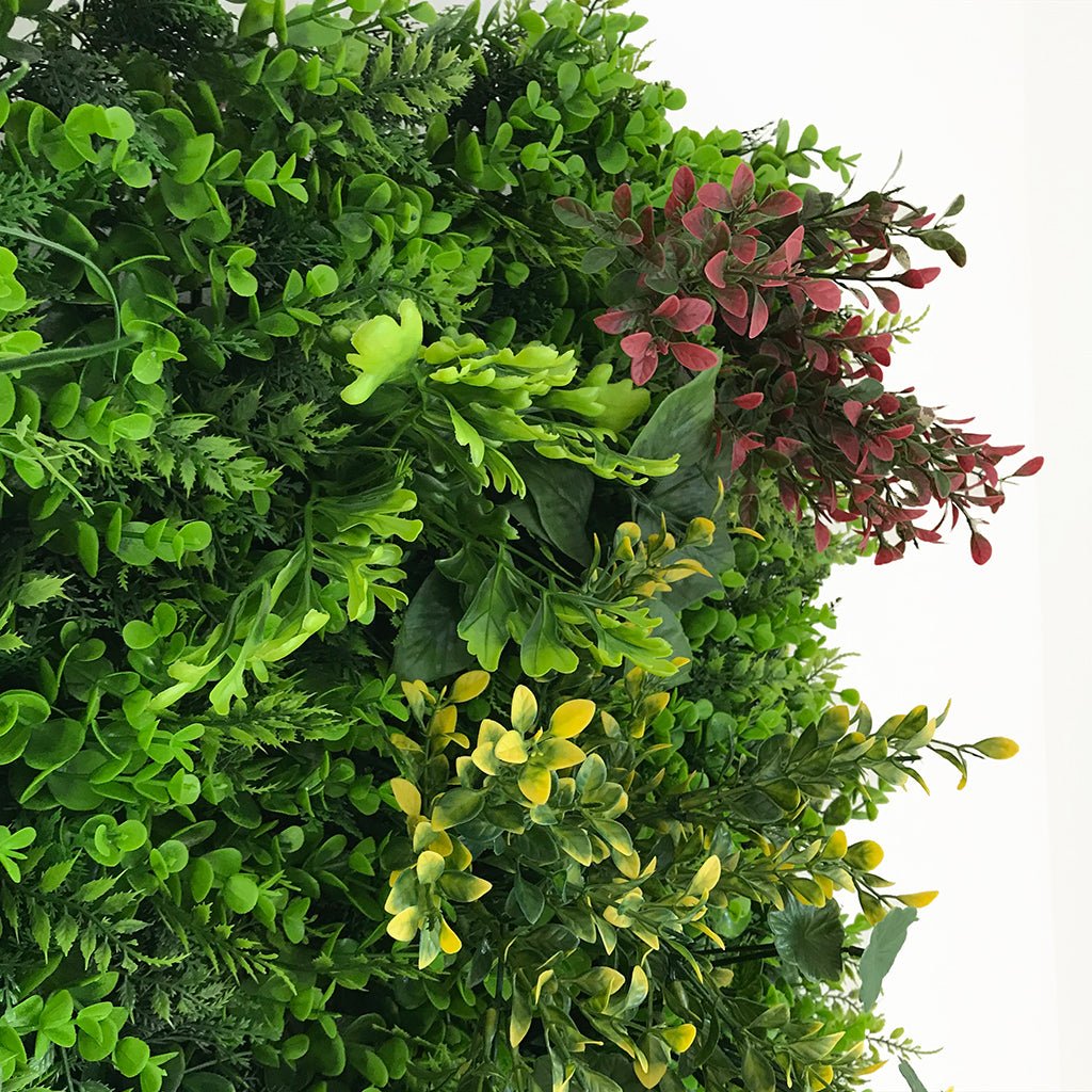 Artificial plant wall panel close-up of green leaves with red and yellow-green accents