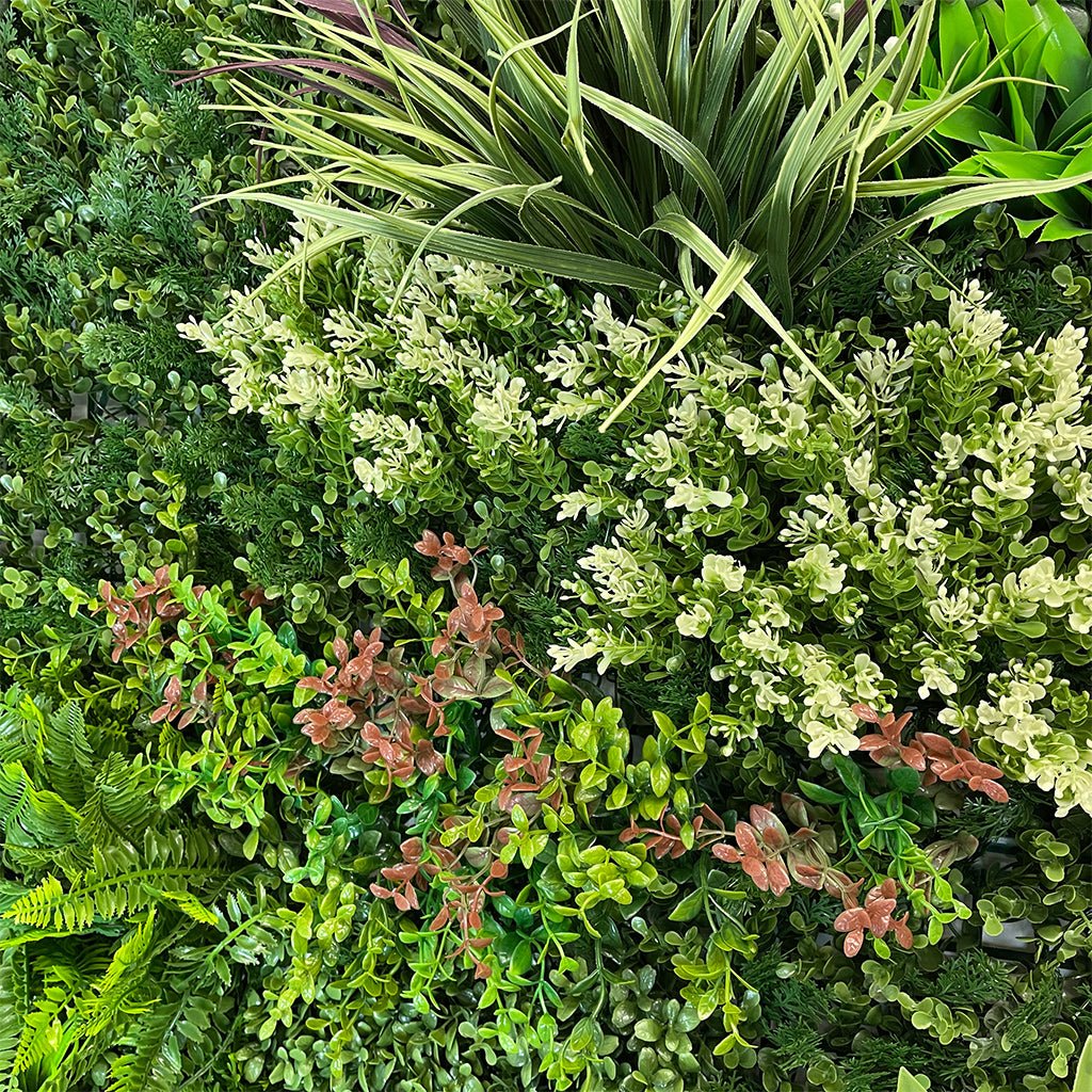 Artificial green foliage wall panel close-up with bright lime leaves and white blooms