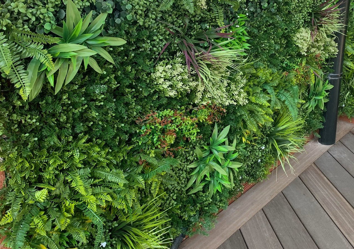 Artificial green foliage wall panel side view with fern fronds and spiky plants