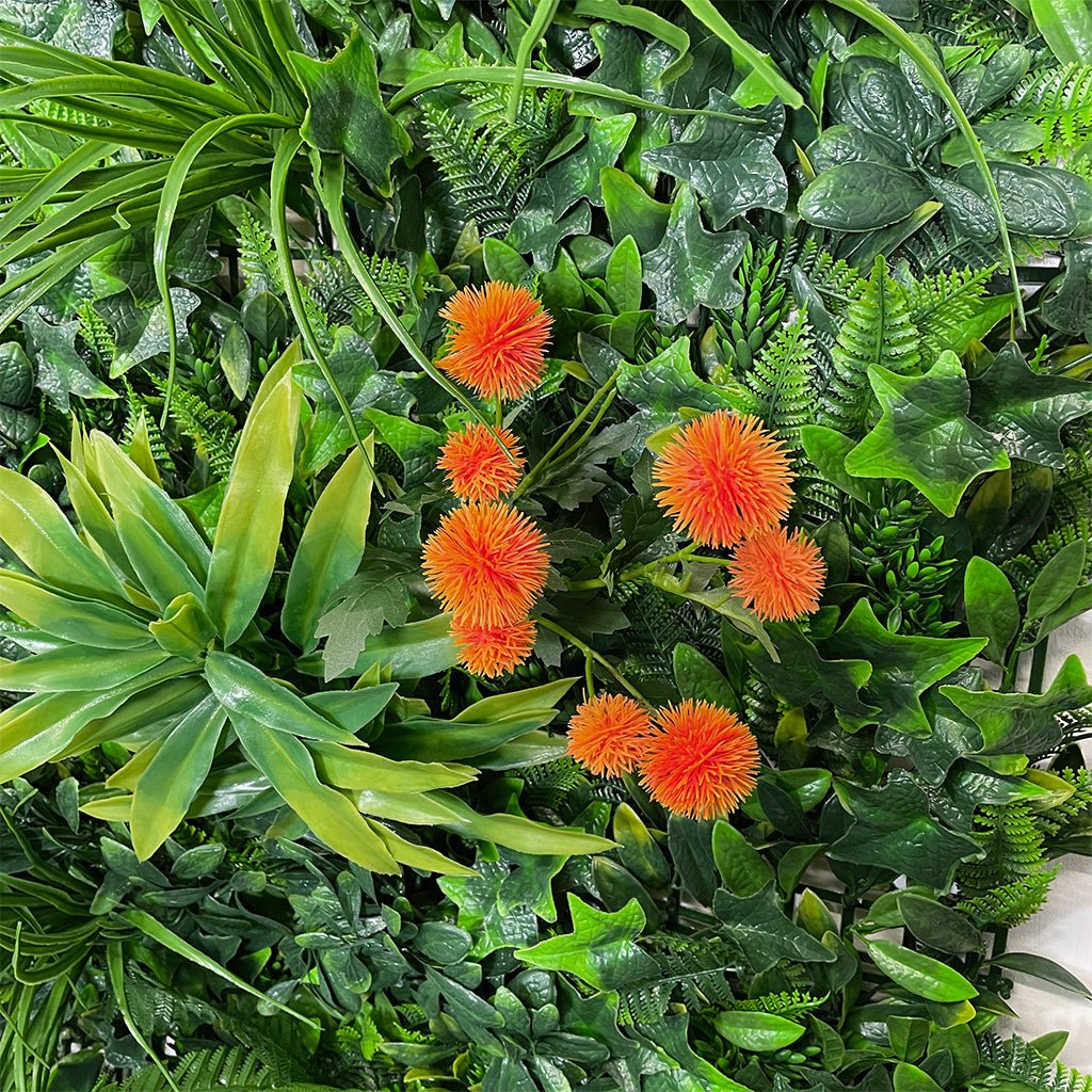 Artificial tropical green foliage wall with orange dahlia-like flowers, dense leafy texture
