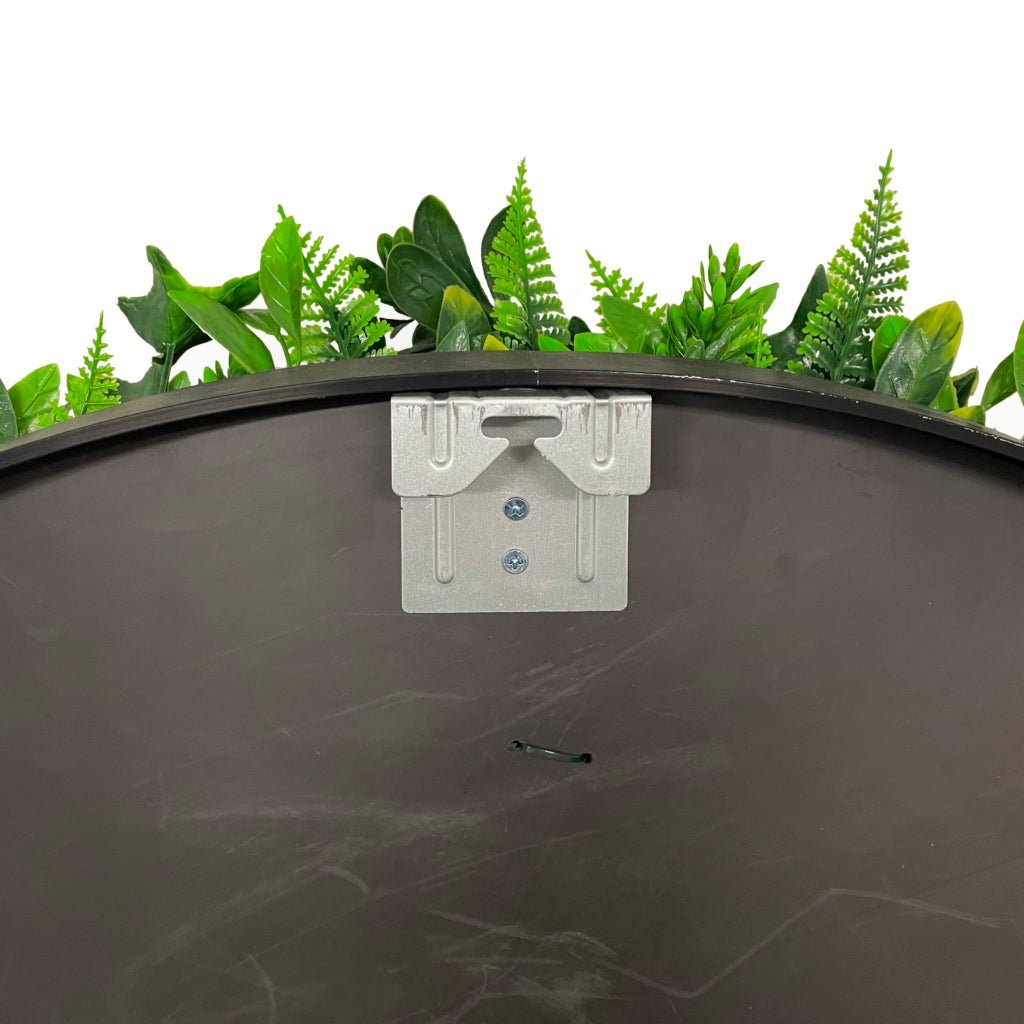Circular artificial foliage wall panel with dark metal rim and mounting bracket