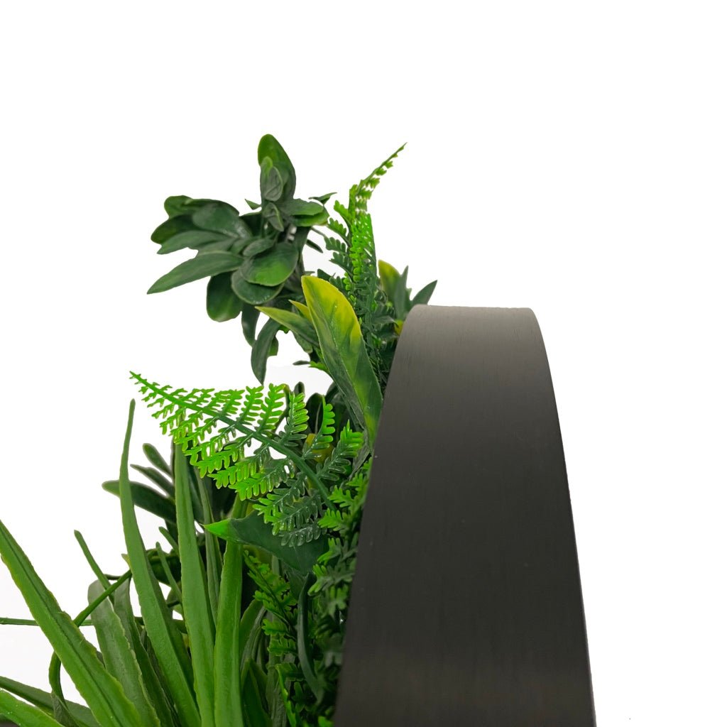 Artificial green foliage wall panel in dark circular frame, side view
