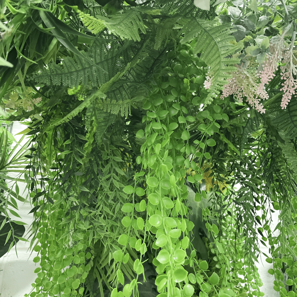 Artificial hanging plant hoop with dense trailing green leaves and fern fronds