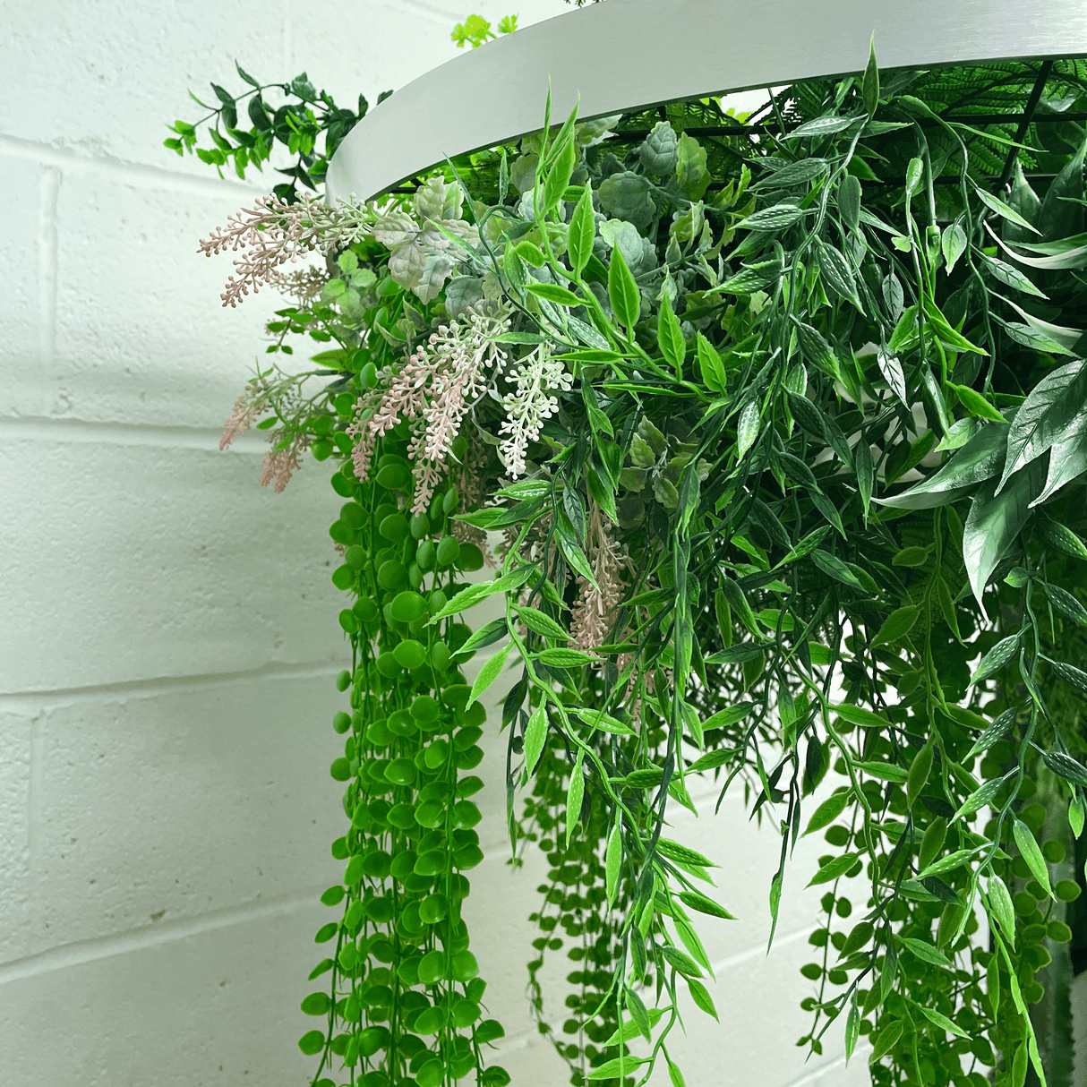 Artificial hanging plant hoop with trailing green leaves and pale pink blossom stems