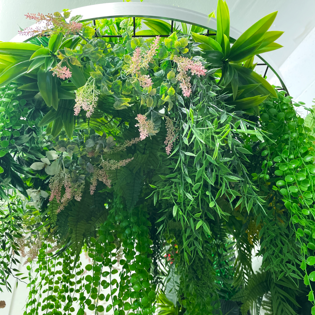 Artificial hanging plant hoop with mixed green foliage and pink, yellow, and orange blooms