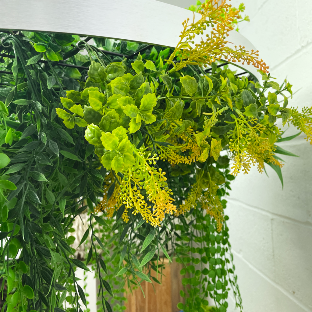 Artificial hanging plant hoop with bright green leaves and yellow flower sprays