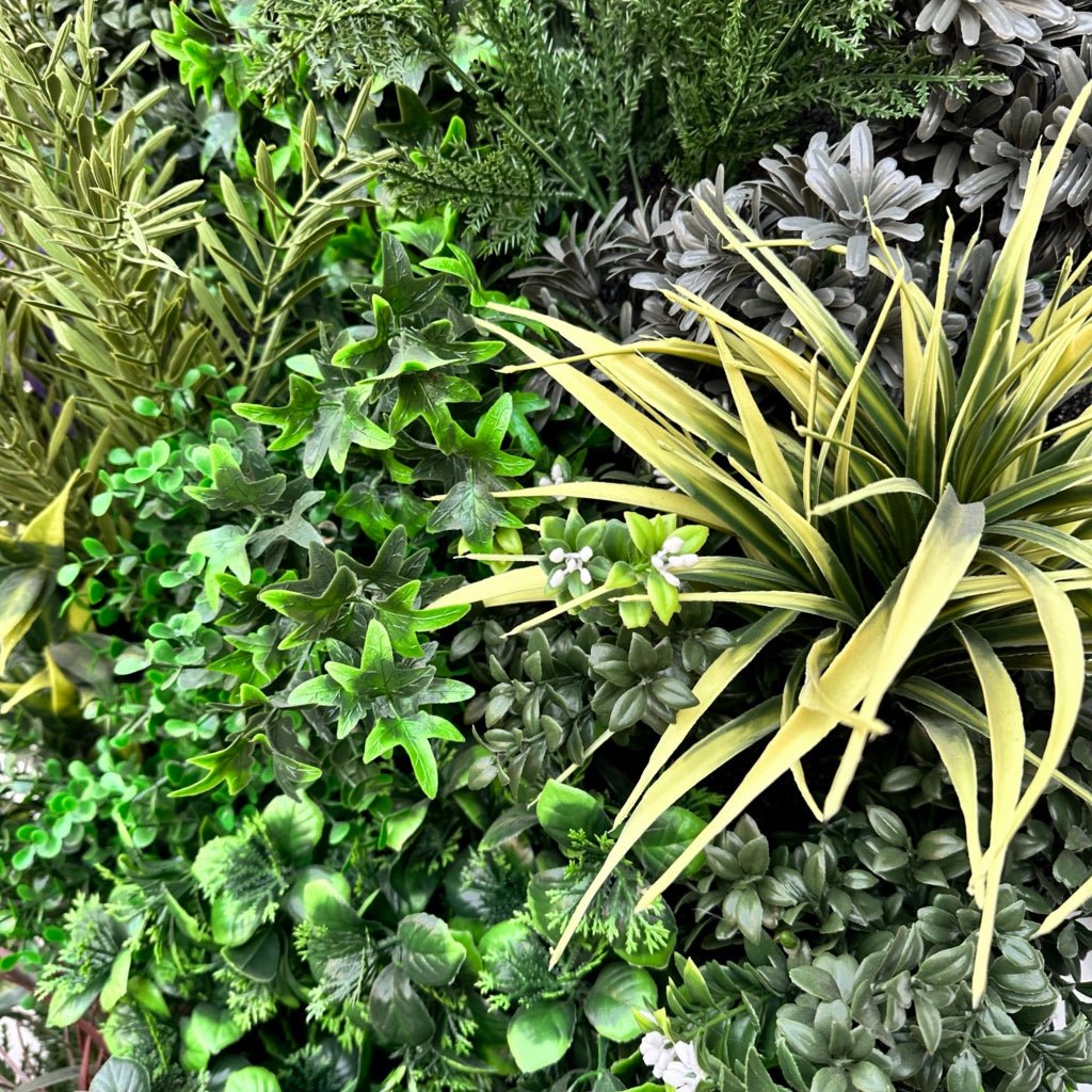 Close-up artificial plant wall with green leaves, pale yellow grass blades, and small blooms