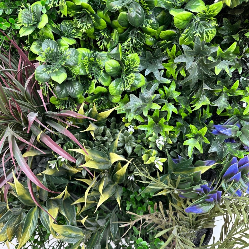 Artificial plant wall close-up with green leaves, magenta stems, and blue-gray accents