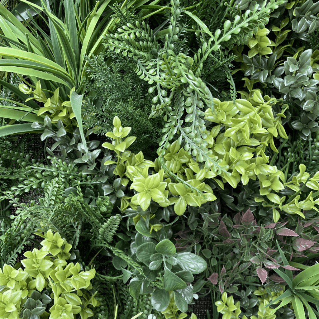 Artificial plant wall panel with dense green and light-yellow foliage, varied leaf textures