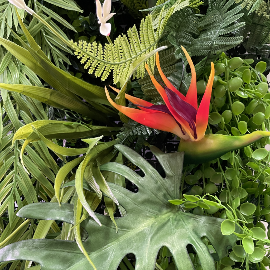 Artificial tropical plant wall panel with green foliage and red-orange bird of paradise flowers
