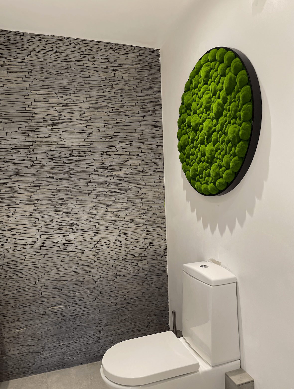 Round moss wall panel on wall: green bun moss texture with dark outer frame.