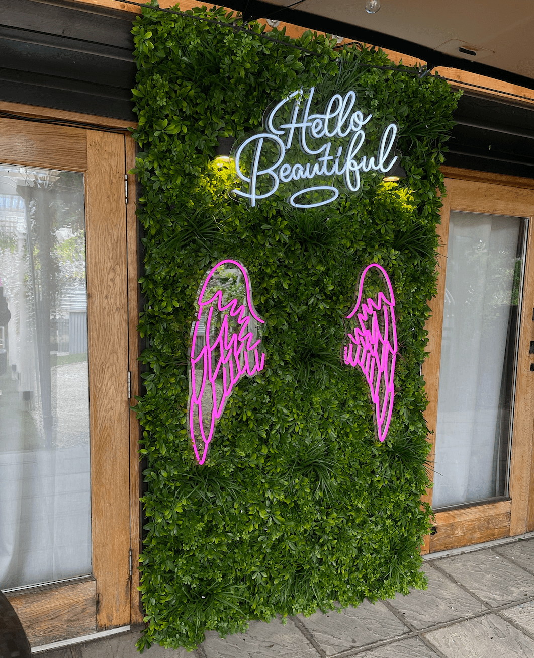 Artificial green foliage wall panel with neon angel line accents