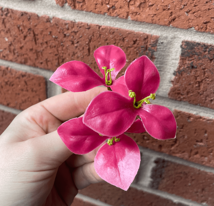 Artificial pink gardenia flower detail on green leafy wall panel
