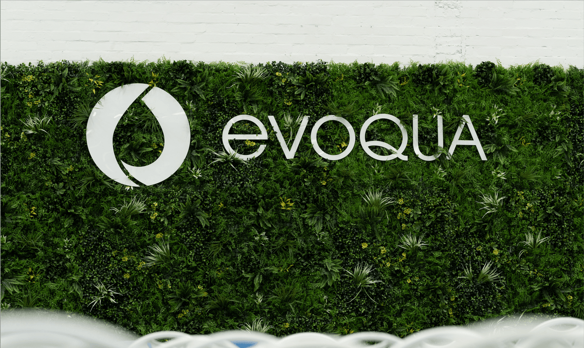 Artificial green wall panel with green hedge texture and evOQUA logo