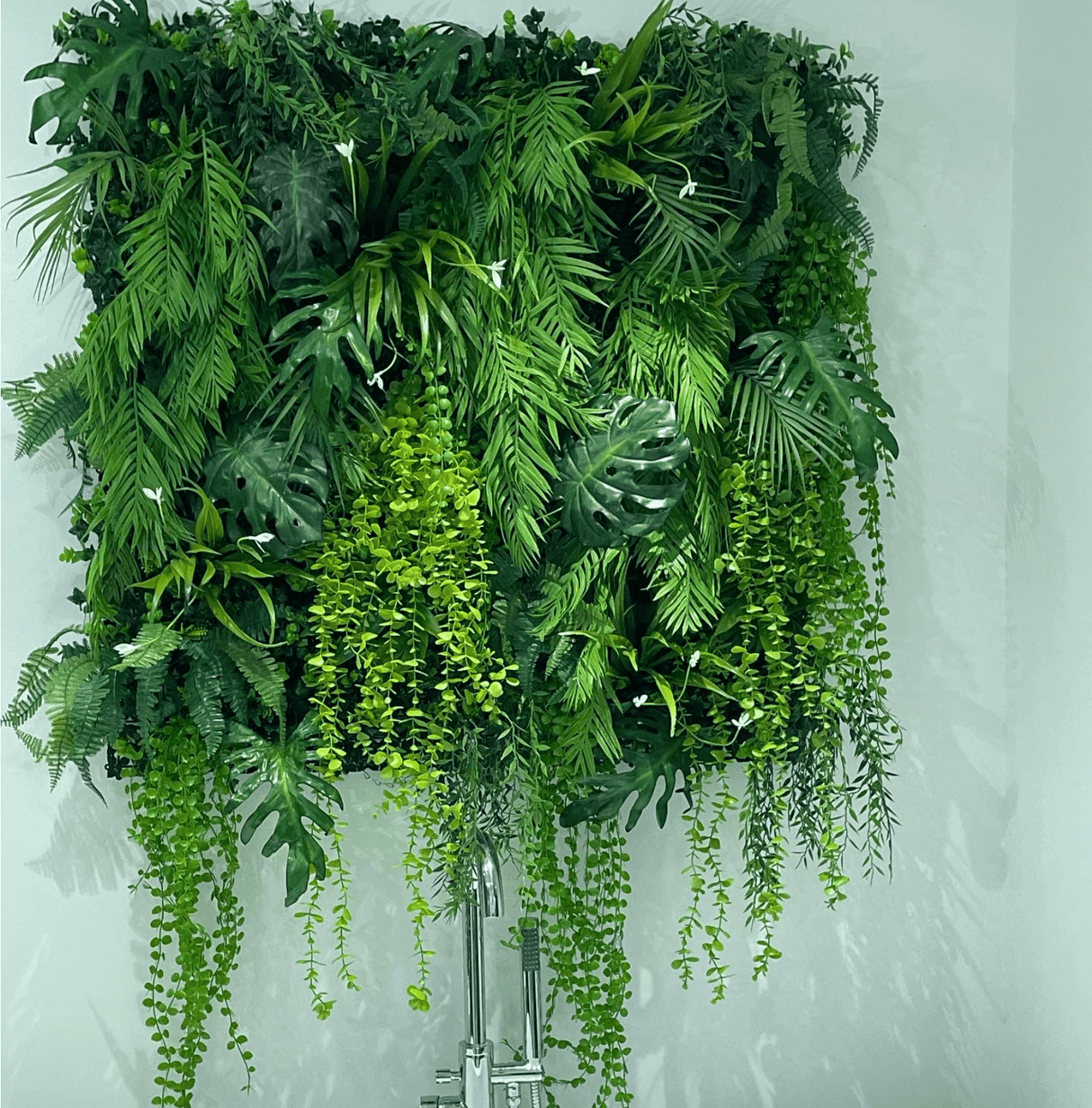 Artificial tropical plant wall with dense green foliage and trailing vine strands