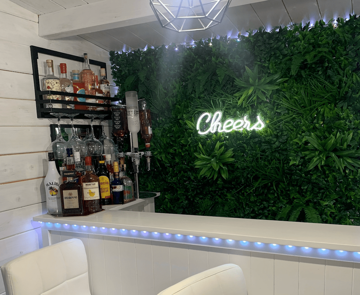 Green artificial foliage wall panel with neon script sign for bar or cafe decor