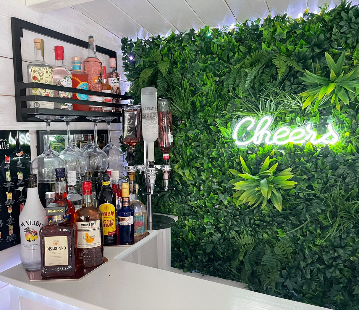 Green artificial foliage wall panel with neon script sign and layered leaf textures