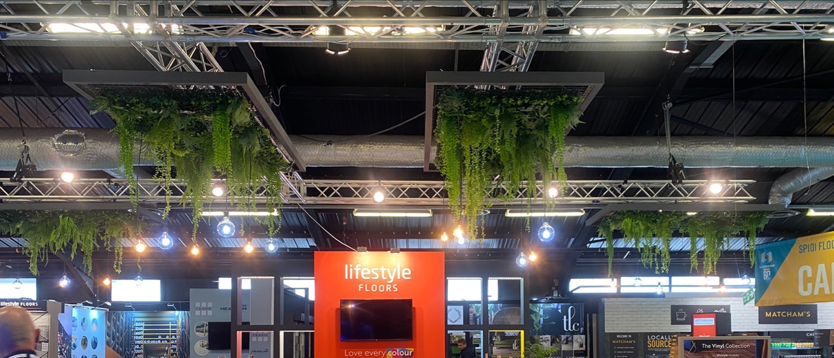 Multiple hanging artificial plant wall panels with trailing green vines