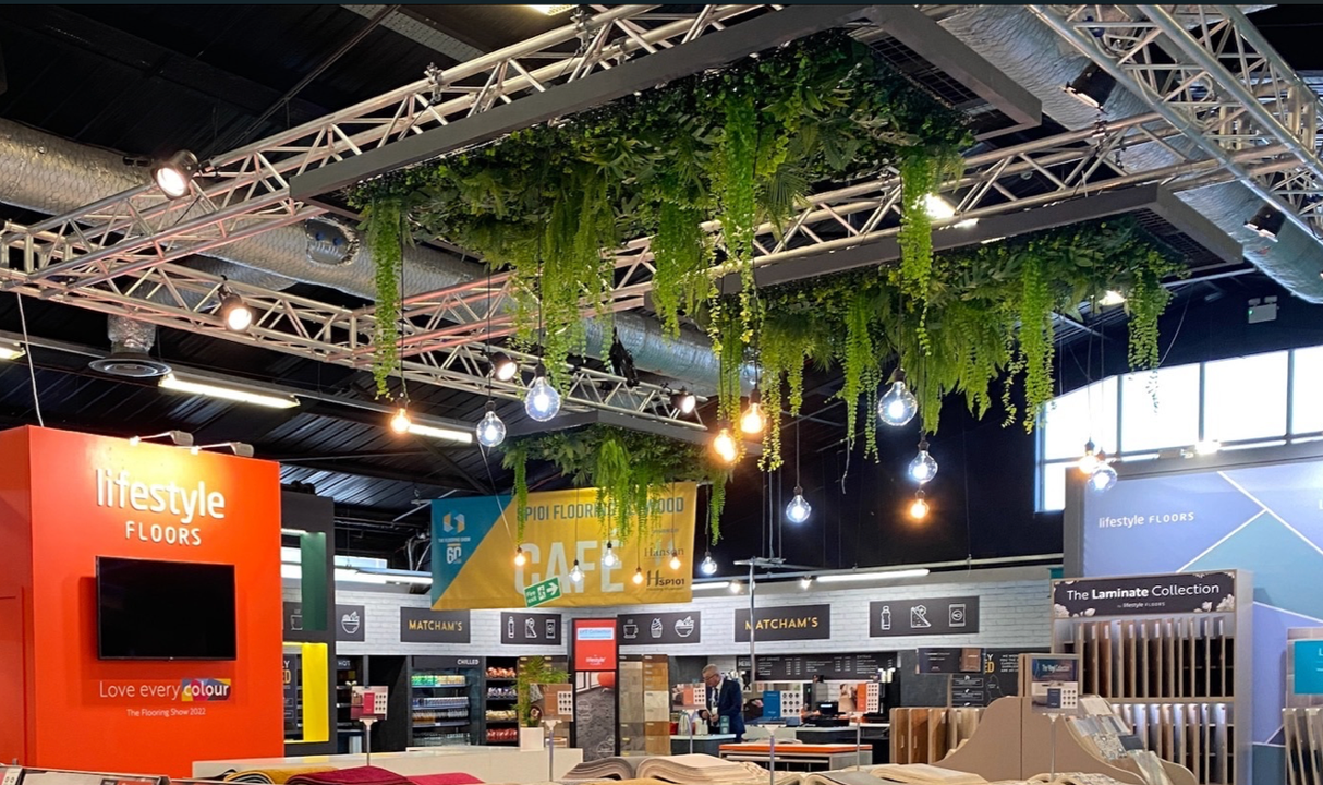 Hanging artificial foliage wall panels with trailing vines under ceiling lights