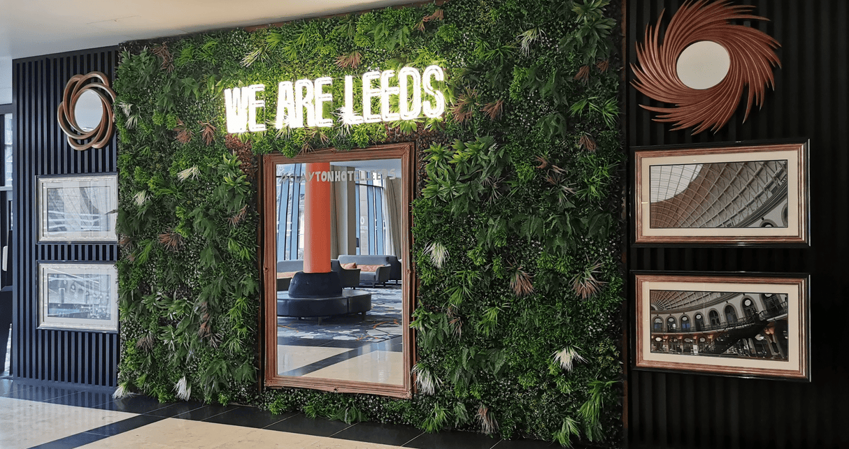 Artificial green wall panel with dense mixed foliage in green, with hints purple and red