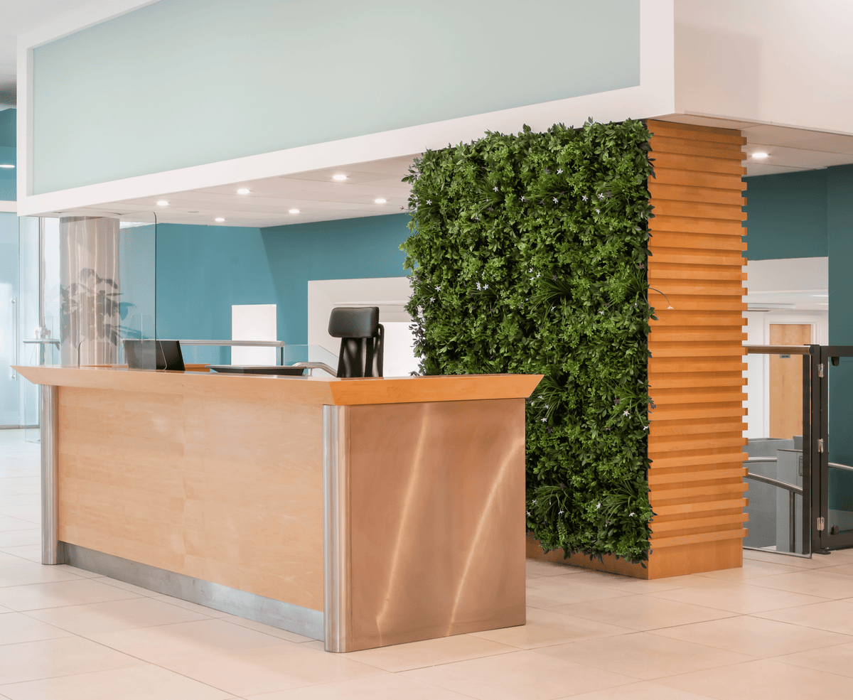 Artificial green foliage wall panel on a vertical wooden partition, dense leaf texture