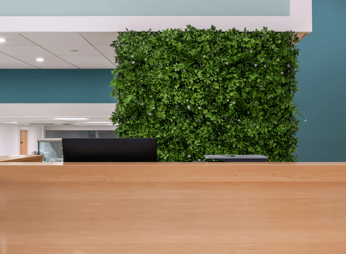 Artificial green foliage wall panel covering a wall section with dense leafy surface