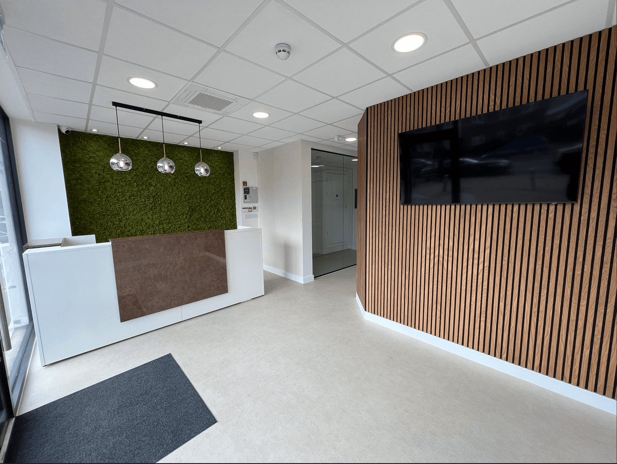 Artificial moss panel feature wall behind reception counter in office
