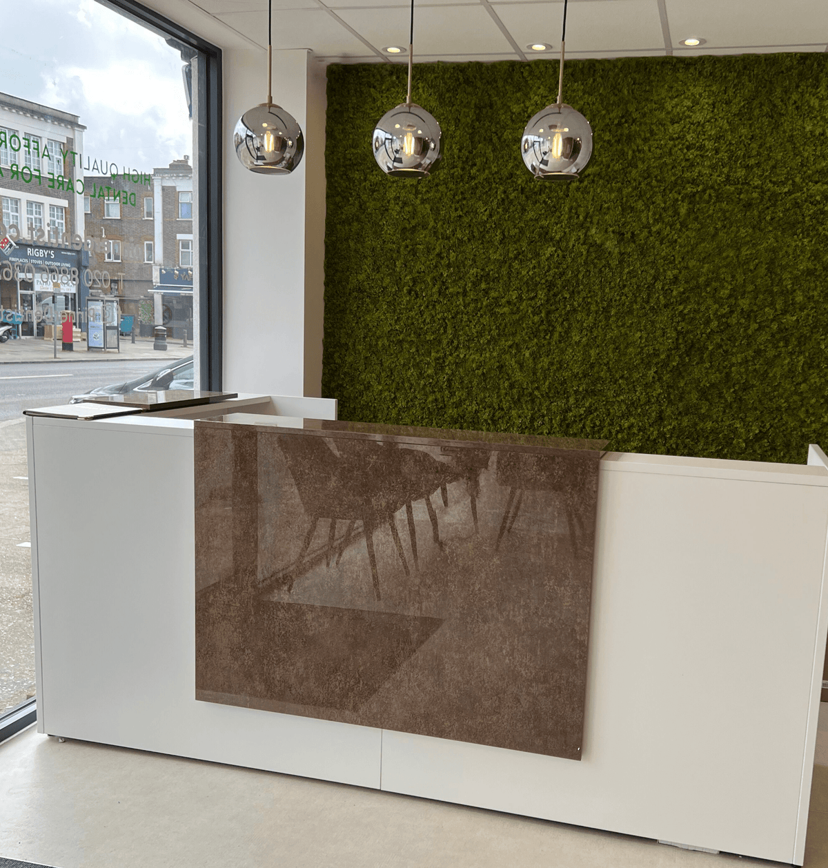 Artificial moss panel feature wall with green texture behind reception counter