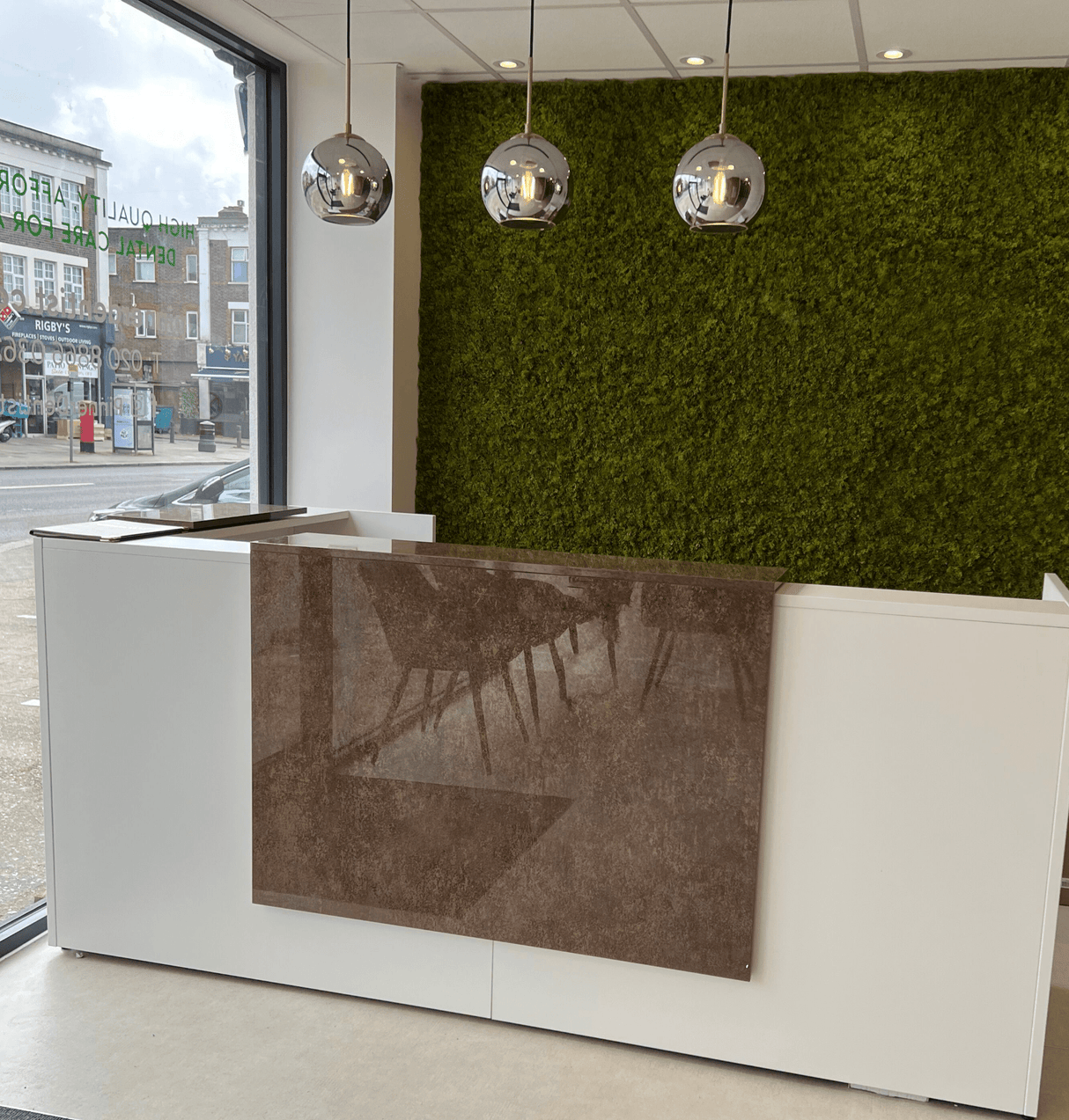Artificial green moss panel covering a wall section behind a reception counter