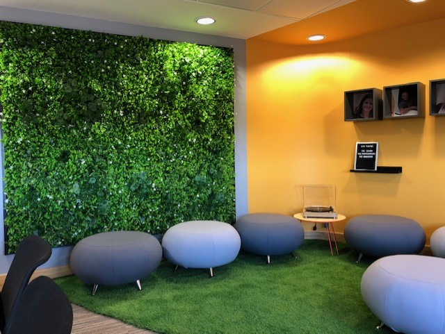 Artificial green plant wall panel installed on an interior wall with dense greenery