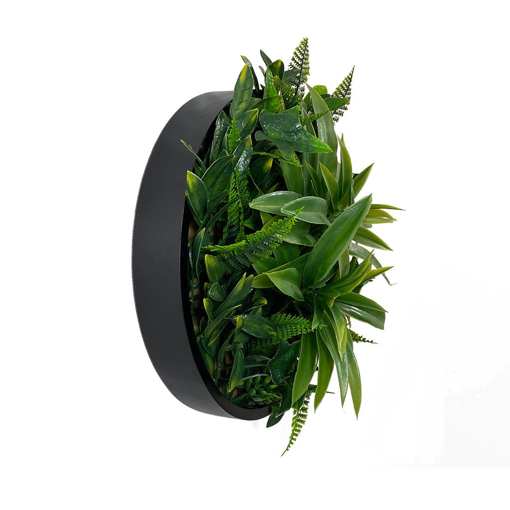 Black circular MDF-backed foliage wall panel with layered green leaves