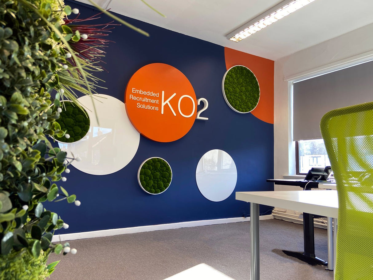 Office wall featuring multiple circular green moss panels with white frames