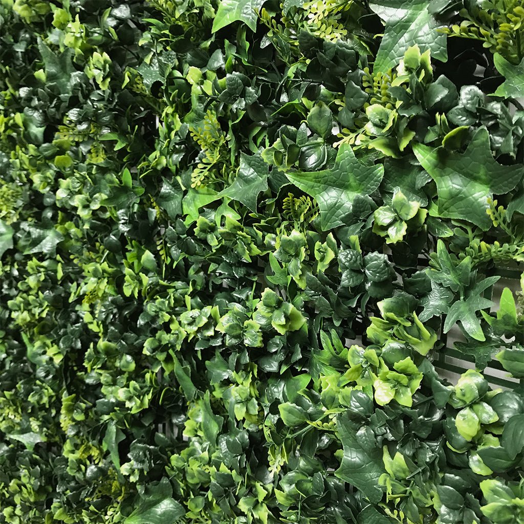 Artificial green wall plant panel close-up of faux leaves and ivy, layered dark and bright green