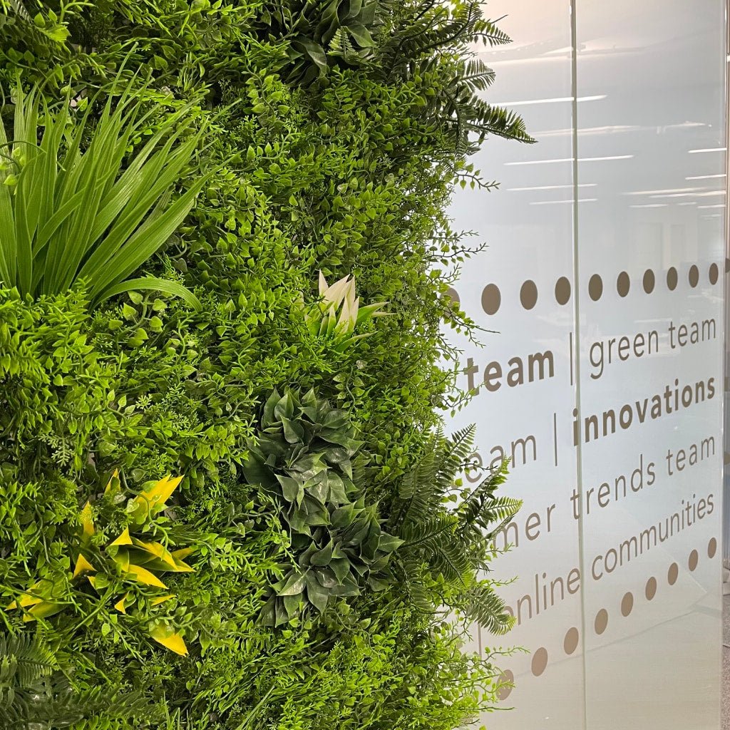 Artificial green wall panel densely packed with fern fronds and small leaf sprigs