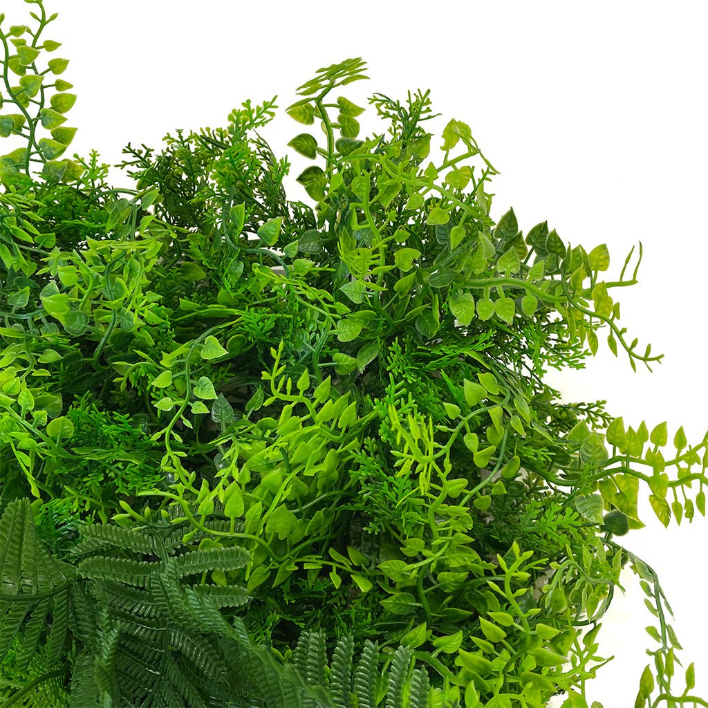 Artificial green wall panel with layered green leaves and pink flower accents