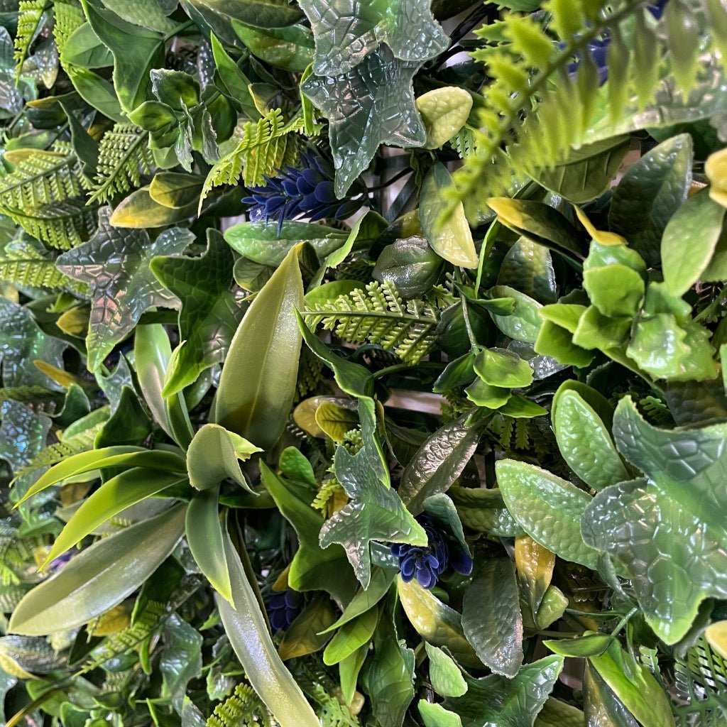 Artificial foliage wall panel close-up with glossy green leaves and blue-purple accents