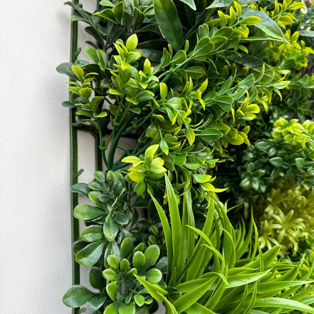 Green foliage wall panel corner with vertical frame and layered leaves