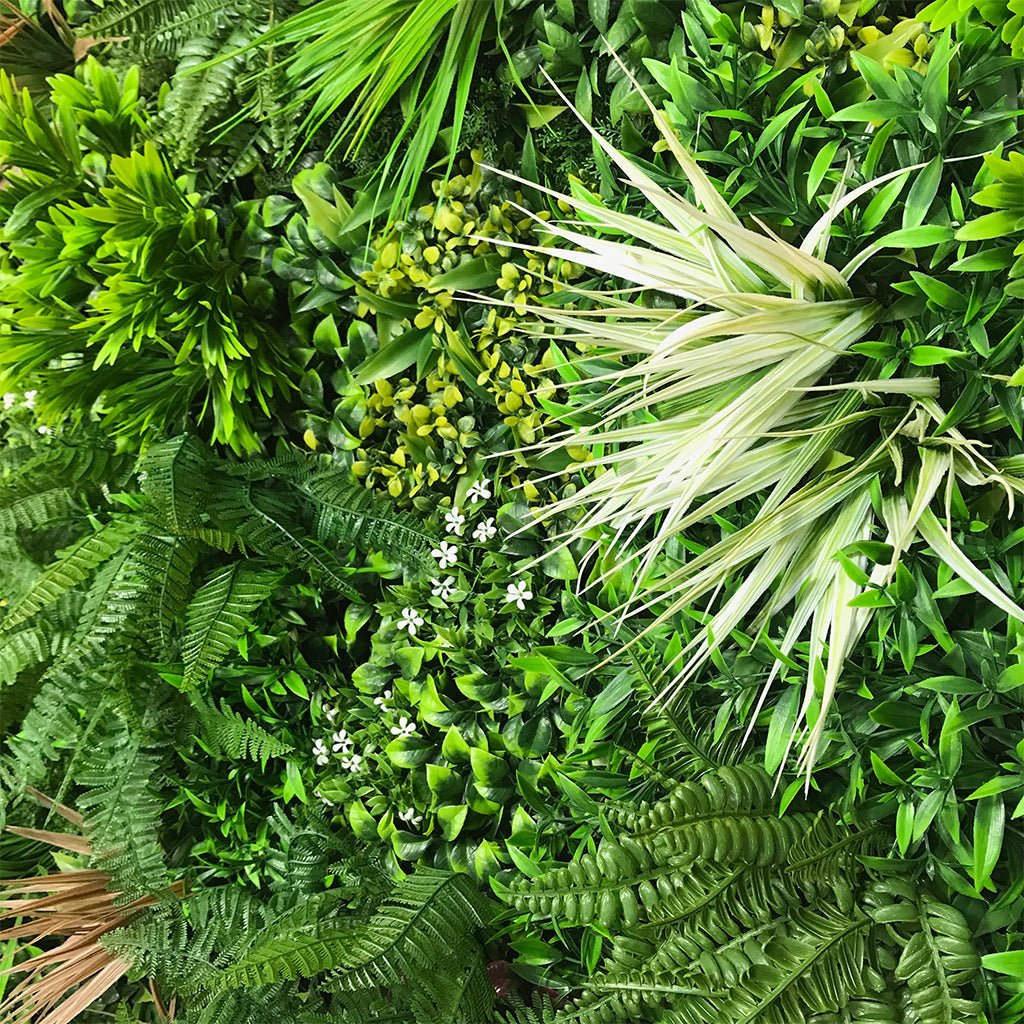 Artificial green wall panel with dense variegated foliage and small white flowers