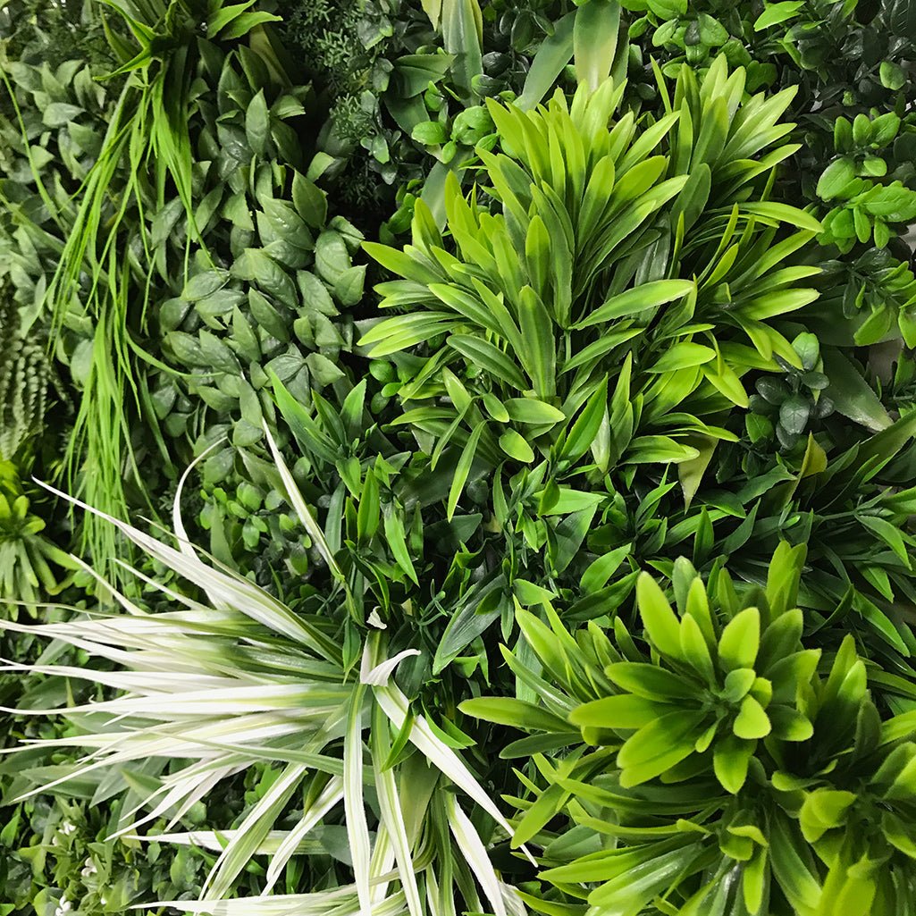 Artificial green foliage wall panel with spiky leaves and small white blossoms