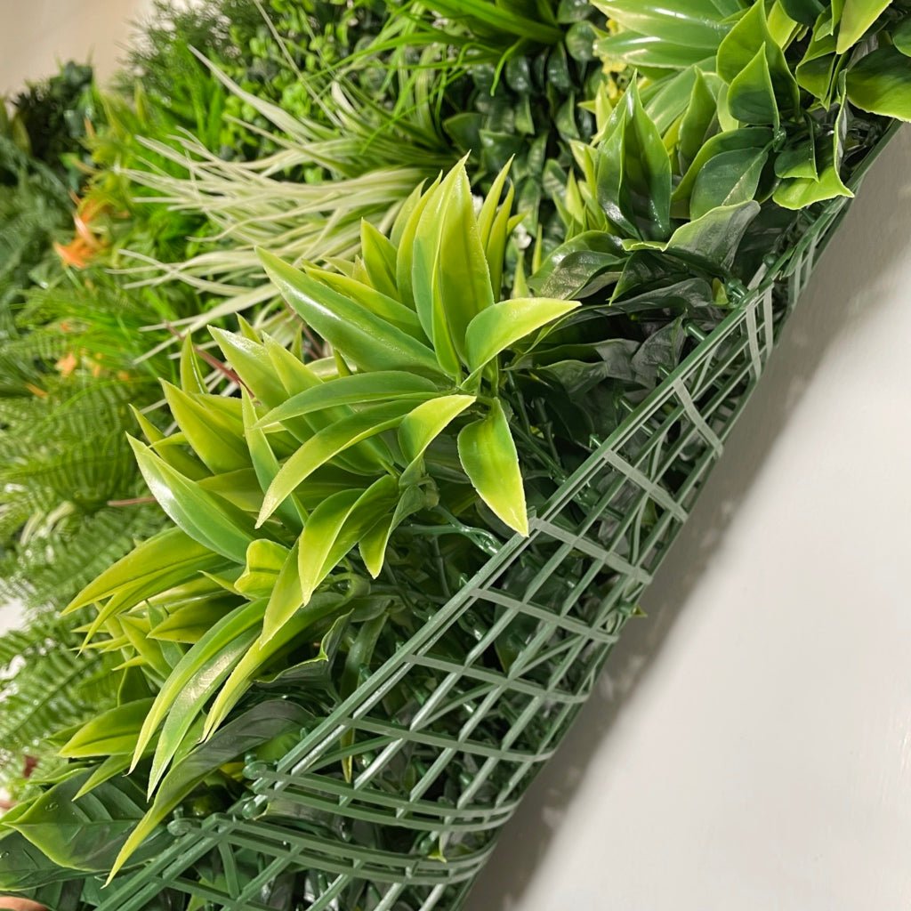 Artificial green foliage wall panel with dense leaves and visible backing grid at corner