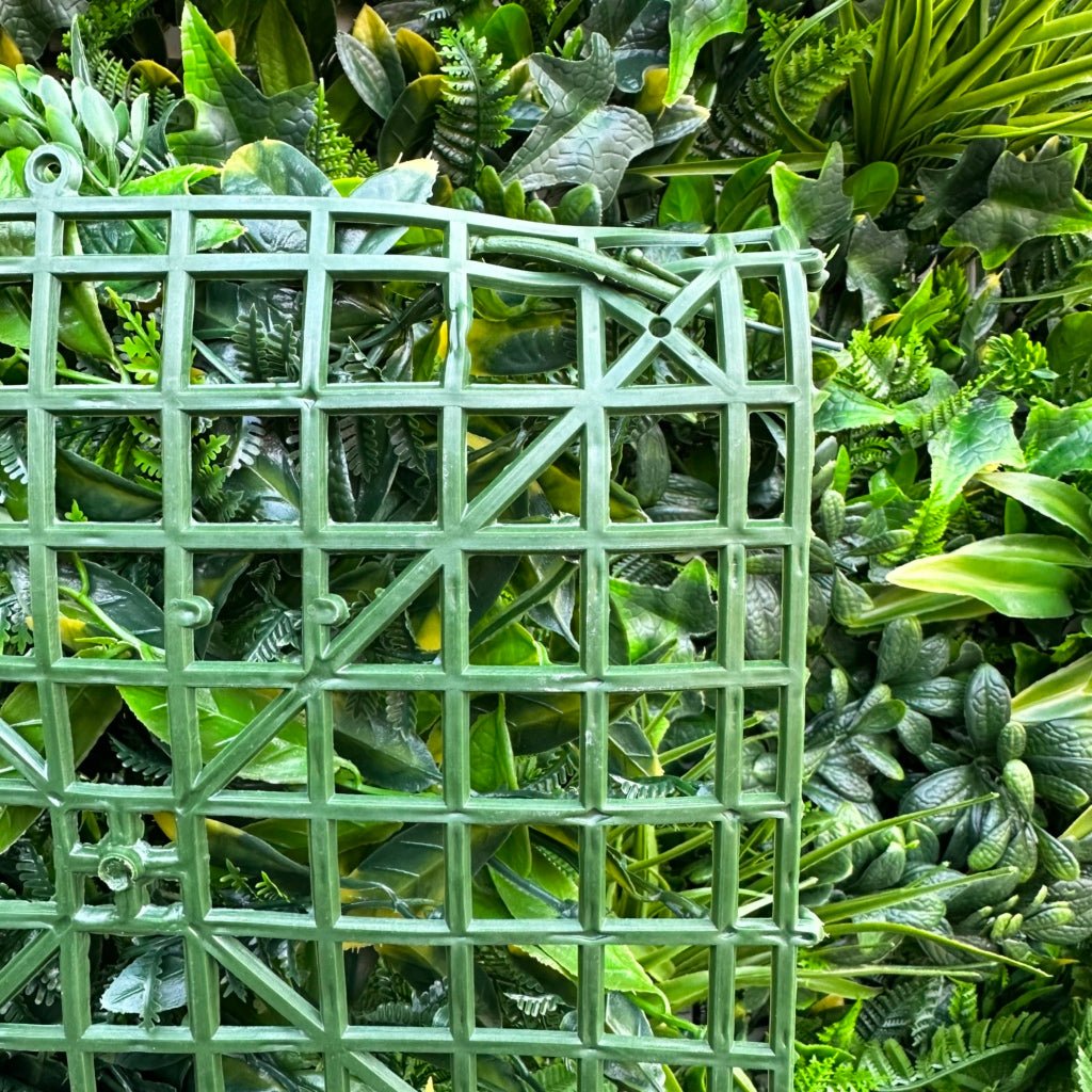 Artificial green foliage wall panel close-up with square grid backing and mixed leaves