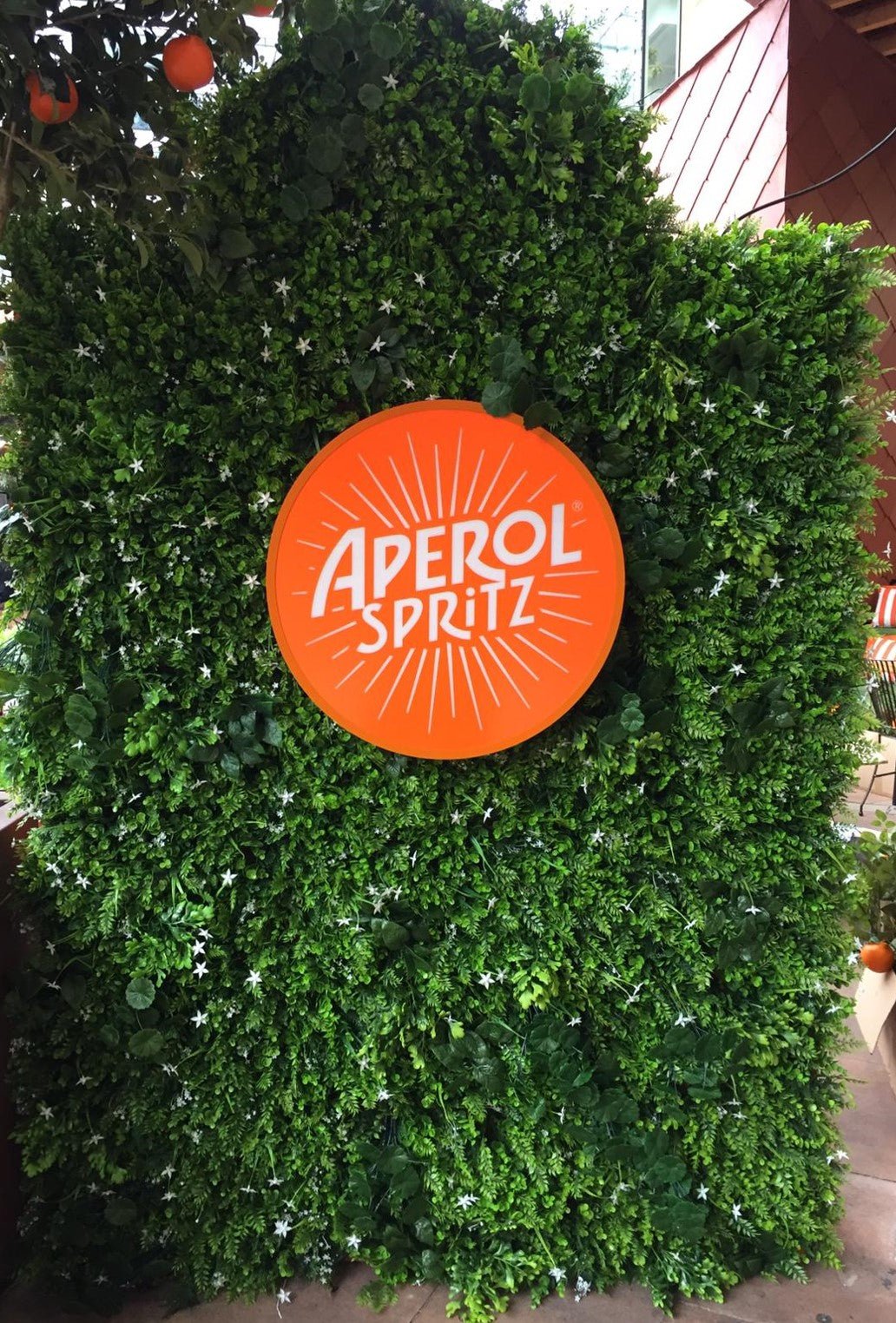 Artificial green plant wall panel with star-like white blossoms, dense foliage