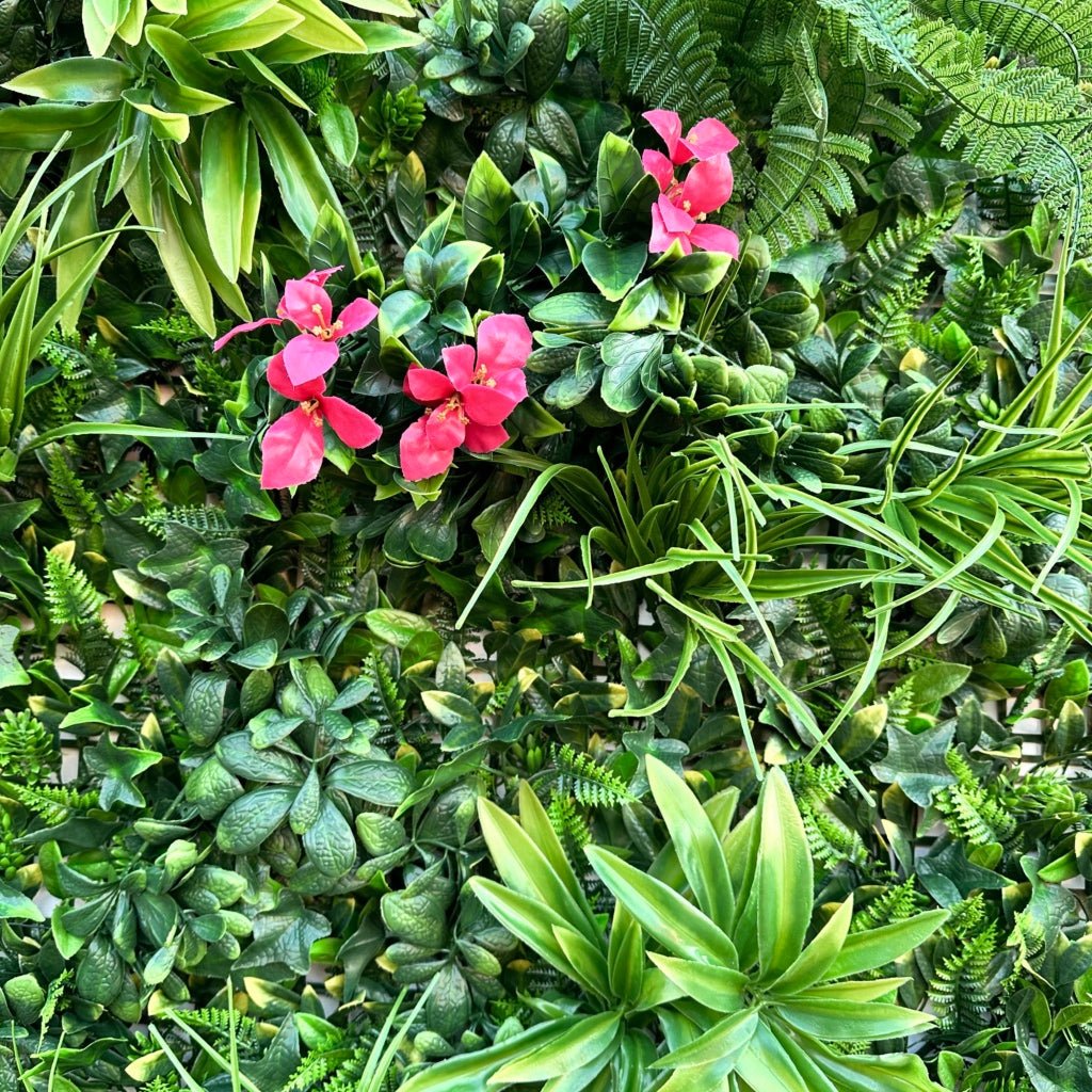 Artificial green foliage wall panel close-up with pink flowers and layered leaves
