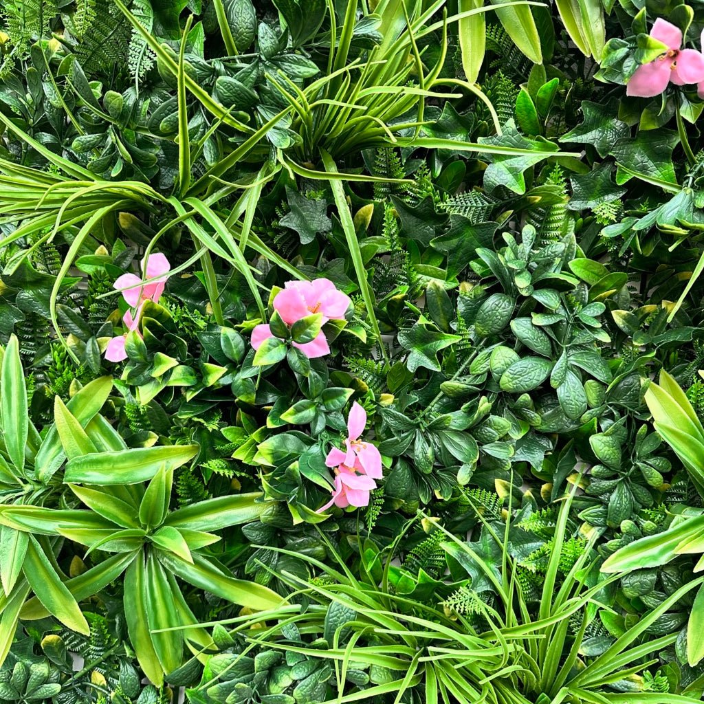 Artificial green foliage wall panel close-up with pink blossoms and palm leaves