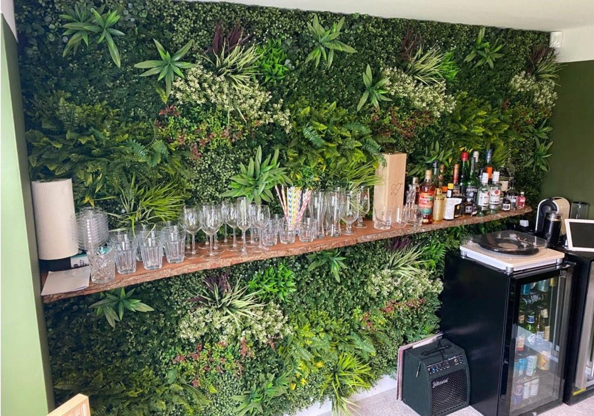 Artificial green foliage wall panel backdrop with tropical leaves and white flower clusters
