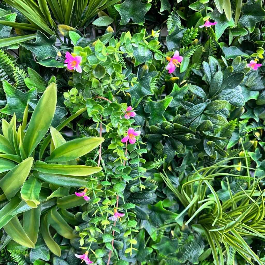 Artificial green foliage wall panel with variegated leaves and small pink flowers
