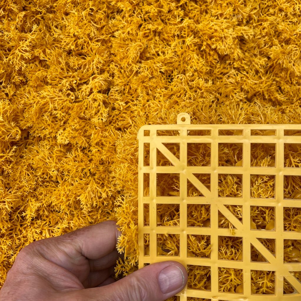 Artificial reindeer moss panel, orange texture with wooden grid held near surface