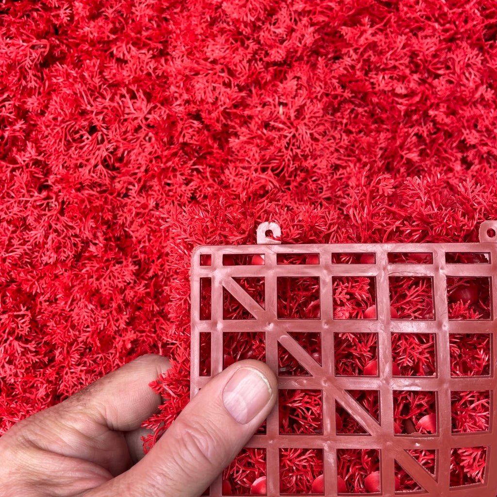 Artificial red moss panel texture, hands showing pile and backing