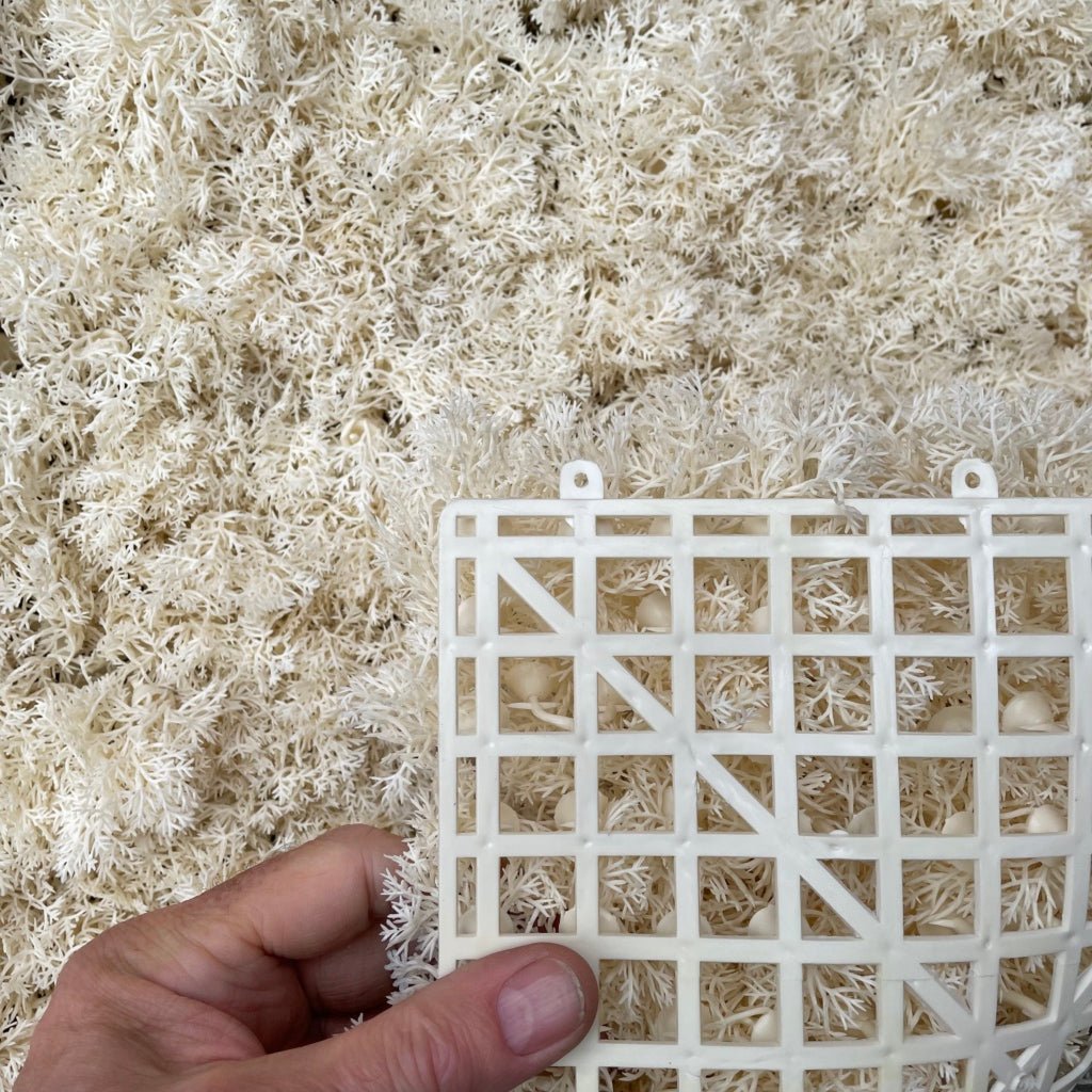 Artificial moss panel tile with white lattice backing, held by hand