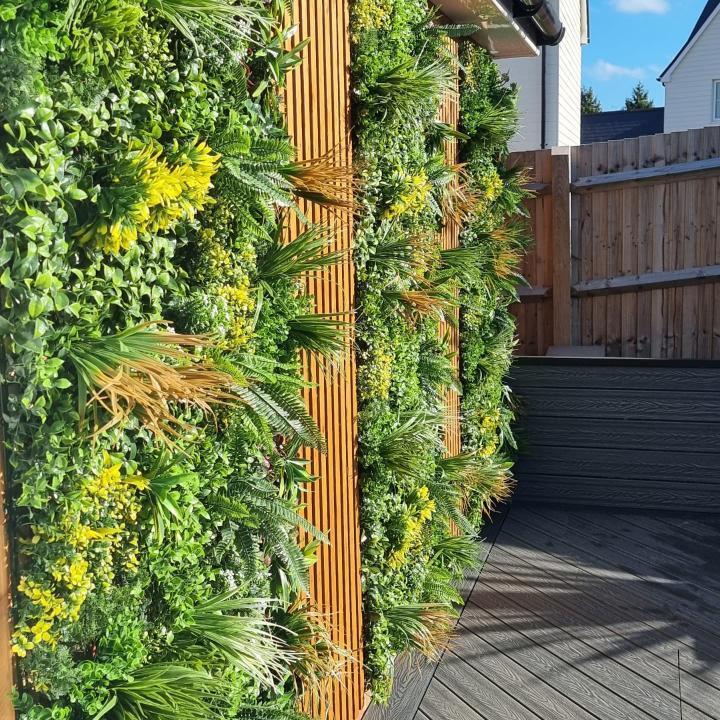 Artificial green wall panel with vertical columns of variegated foliage and layered leaves